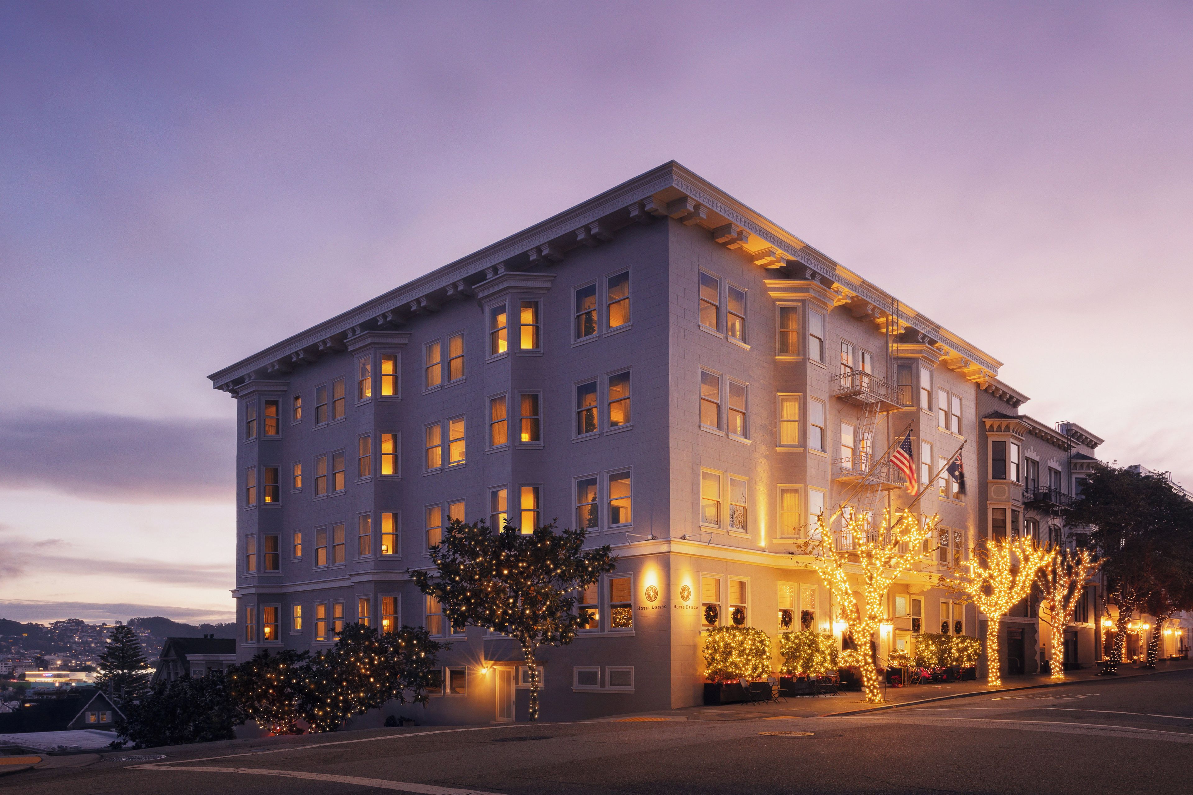 A multi-story hotel with a classic architectural style, featuring a symmetrical facade, multiple windows, and a corner entrance.