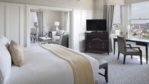 Quarto de hotel com uma cama grande, escrivaninha, televisão e vista para a cidade.