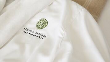 Et hvidt tøj med et grønt logo og tekst, der viser "HOTEL DRISCO PACIFIC HIGHTS".