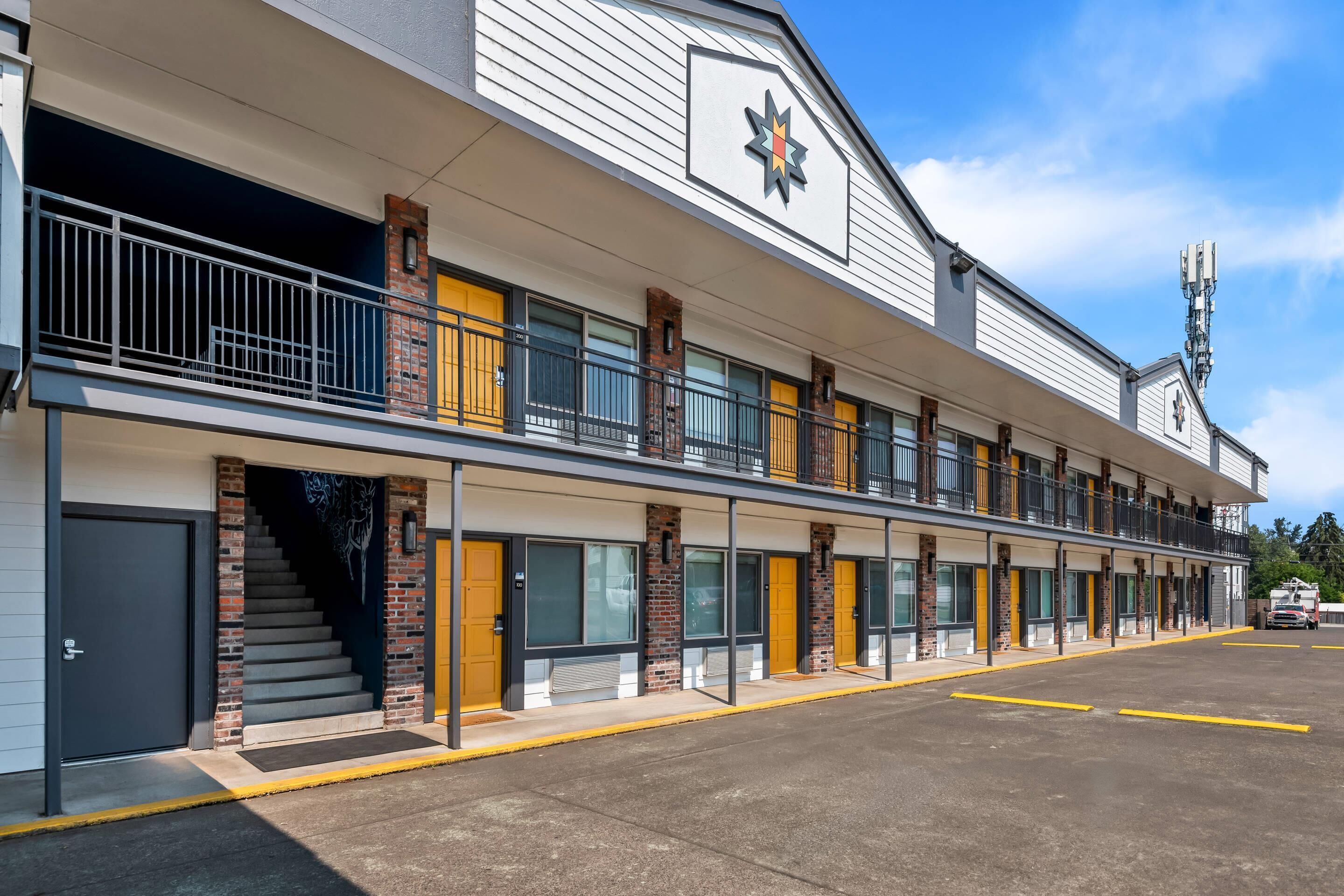 Un motel avec une rangée de chambres, un escalier et un parking.