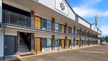 A motel with a row of rooms, a staircase, and a parking lot.