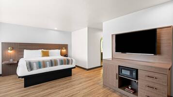 Moderni hotellihuone, jossa on suuri sänky, litteänäyttöinen televisio, sisäänrakennettu mikroaaltouuni ja puinen kaappi.