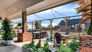 An outdoor patio area with brick planters, wooden tables, and chairs. - Maverick Hotel Eugene Near University, an Ascend Collection Hotel (Eugene)