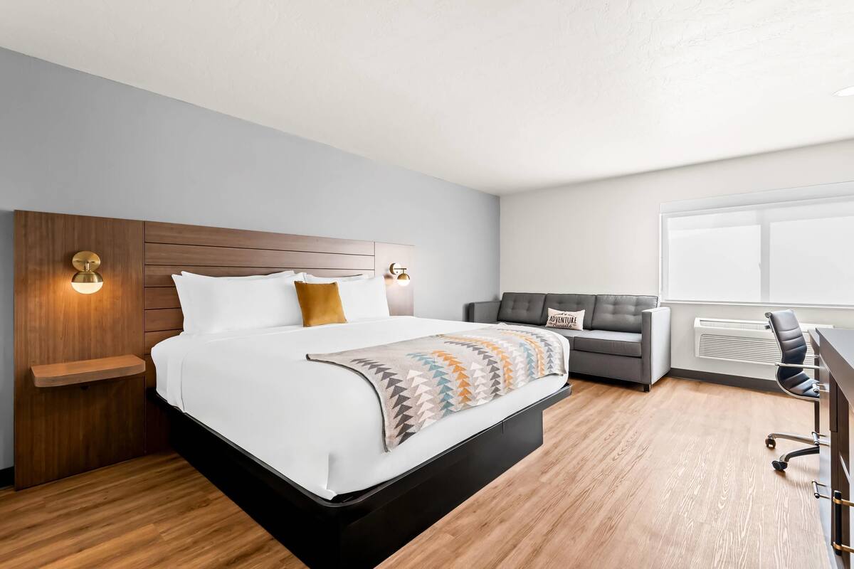 Una habitación de hotel moderna con una cama grande, un sofá, un escritorio y una ventana.
