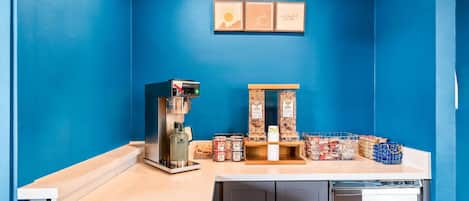 A coffee station with a coffee machine, a grinder, and various coffee pods and containers.