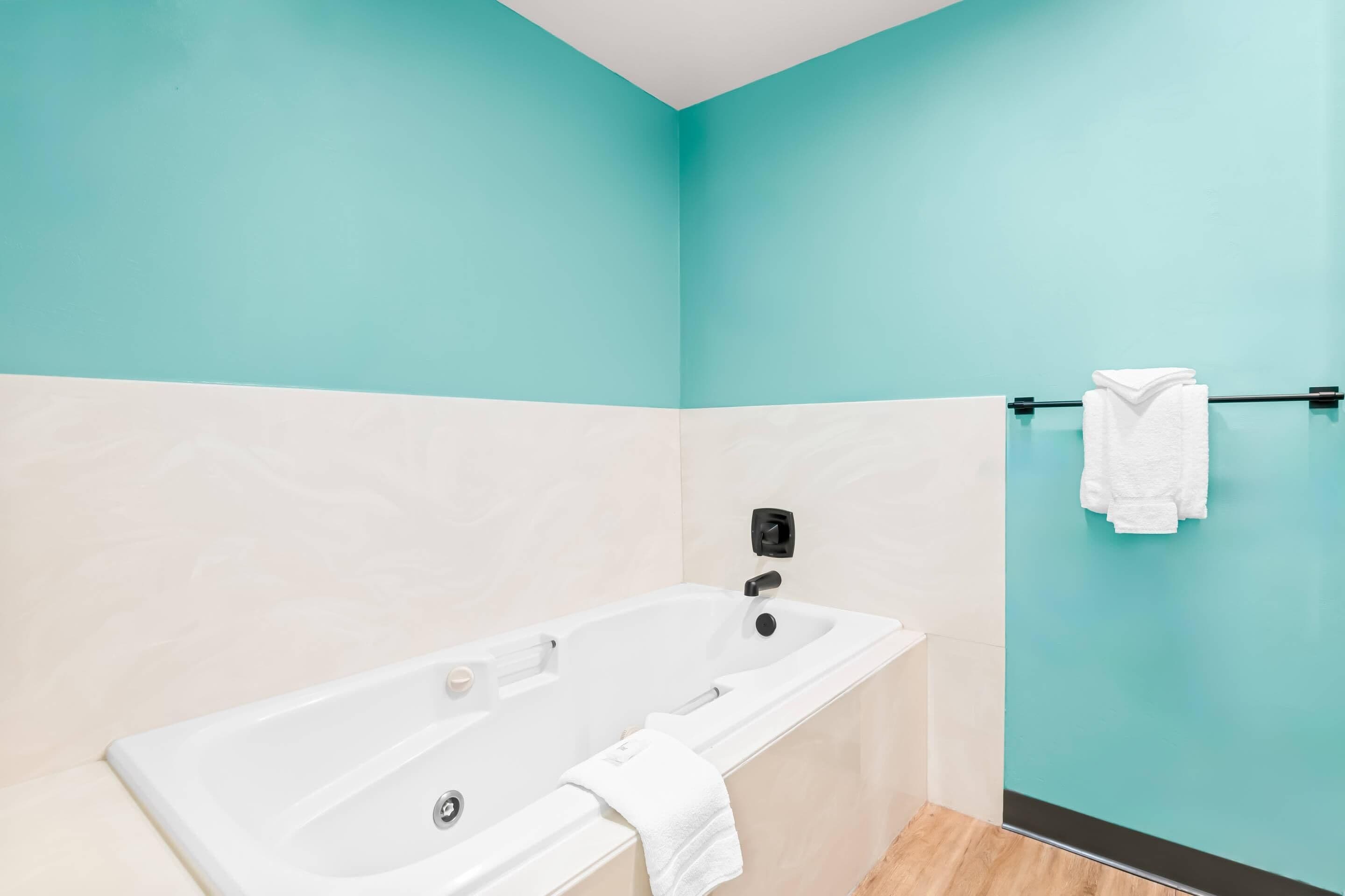 A modern bathroom with a bathtub, a towel rack, and a wall-mounted towel dispenser.