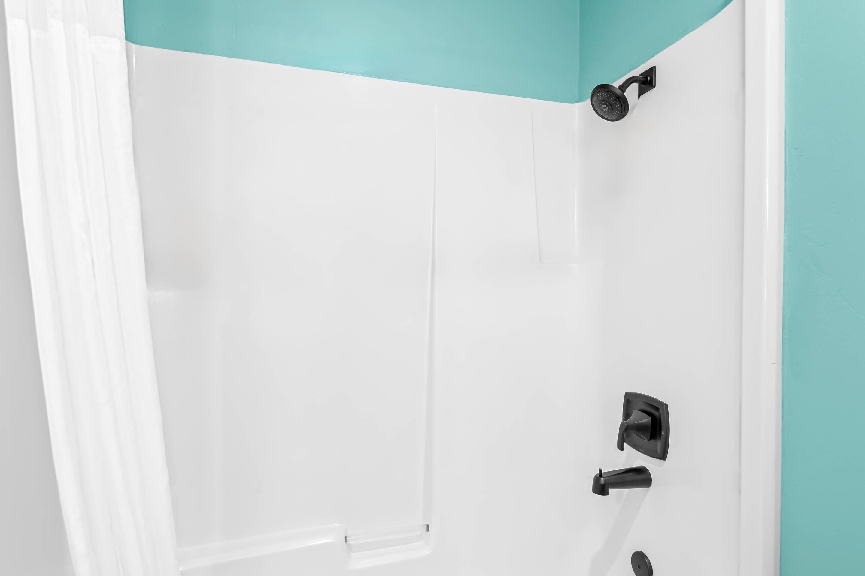 A bathroom with a white shower enclosure, a black showerhead, and a white door with a black handle.