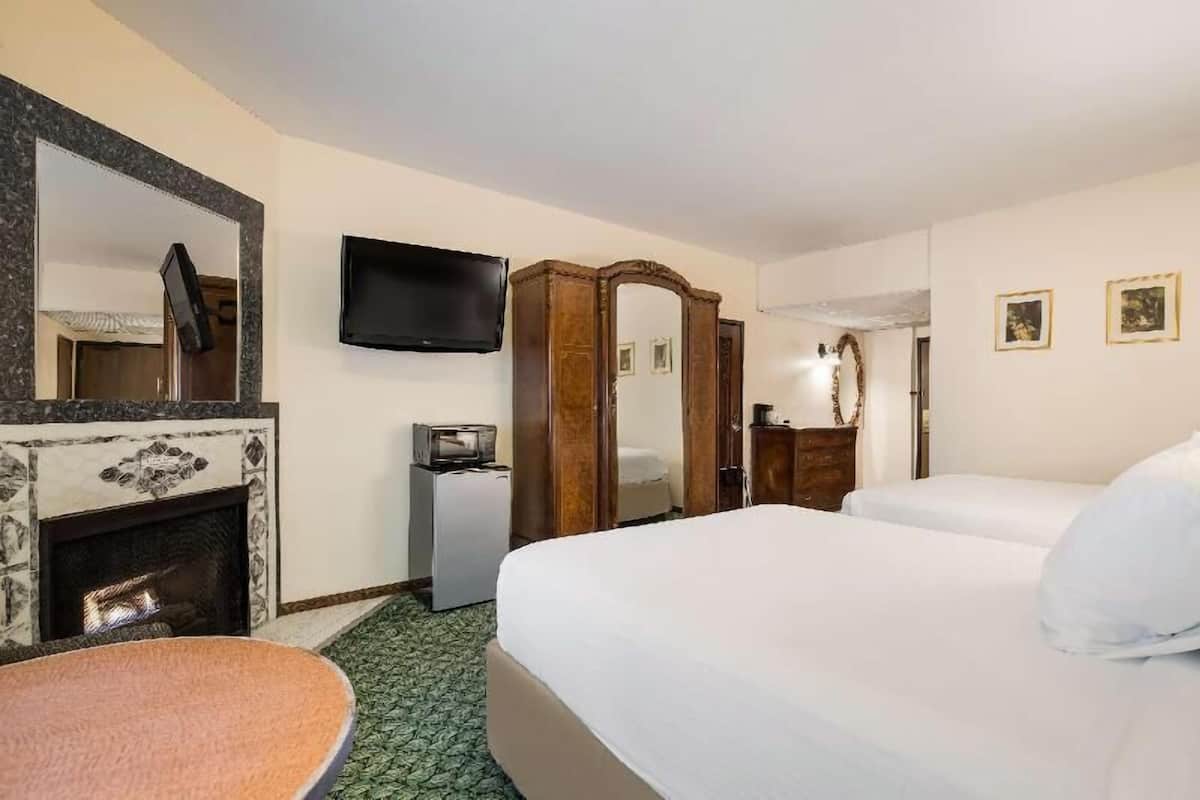 Une chambre d’hôtel équipée d’une cheminée, d’une télévision, d’un lit, d’un bureau et d’un miroir.