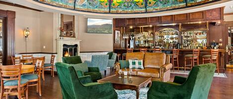 A spacious lobby with a bar area, green upholstered seating, and a decorative glass ceiling.