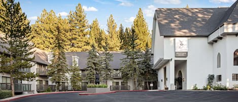 A boutique hotel with a modern architectural style, featuring a prominent signboard and a well-maintained outdoor area with trees and a parking lot.