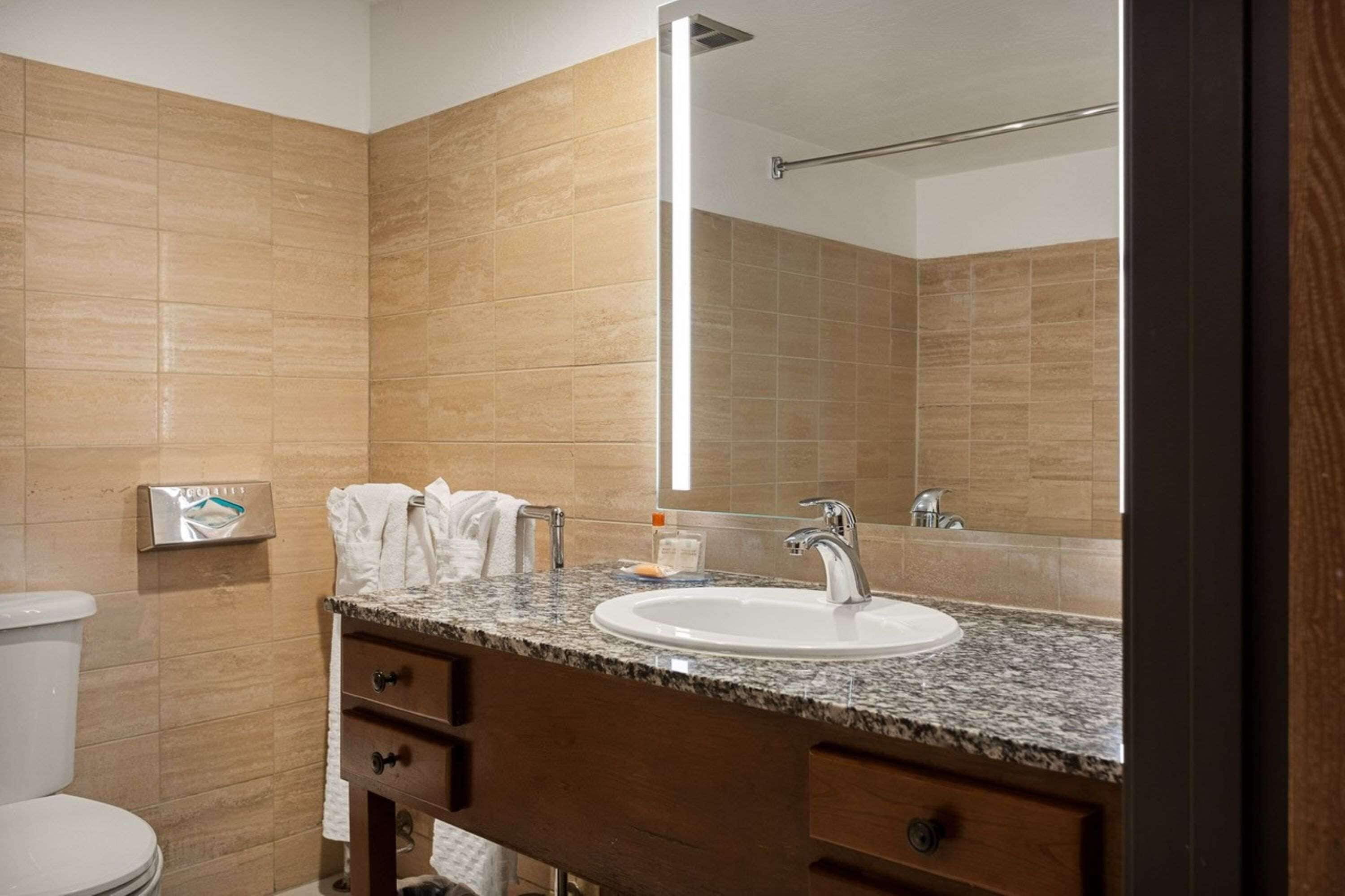 Une salle de bain avec un lavabo en marbre, un porte-serviettes et un miroir.