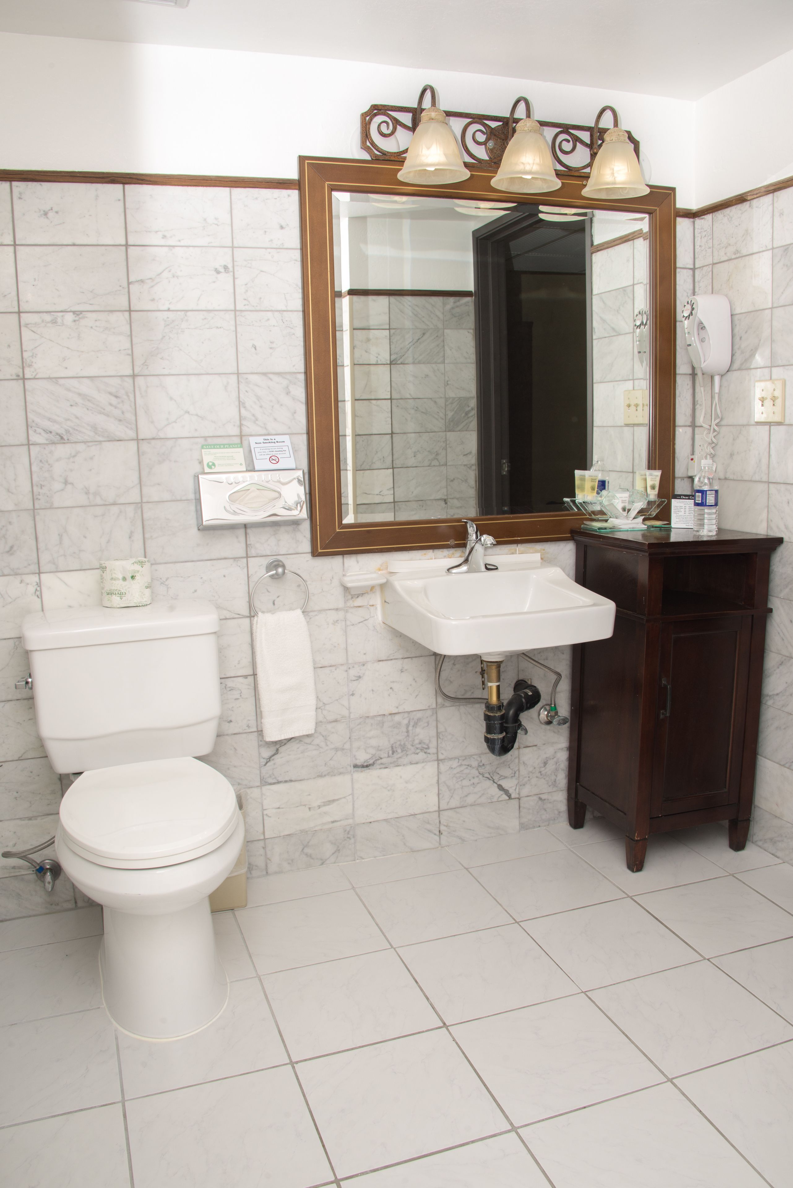 A bathroom with a toilet, sink, and mirror.