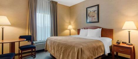 A hotel room with a bed, two bedside tables with lamps, a chair, and a window with curtains.