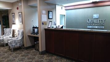 A hotel reception area with a reception desk, framed pictures on the wall, and a carpeted floor.