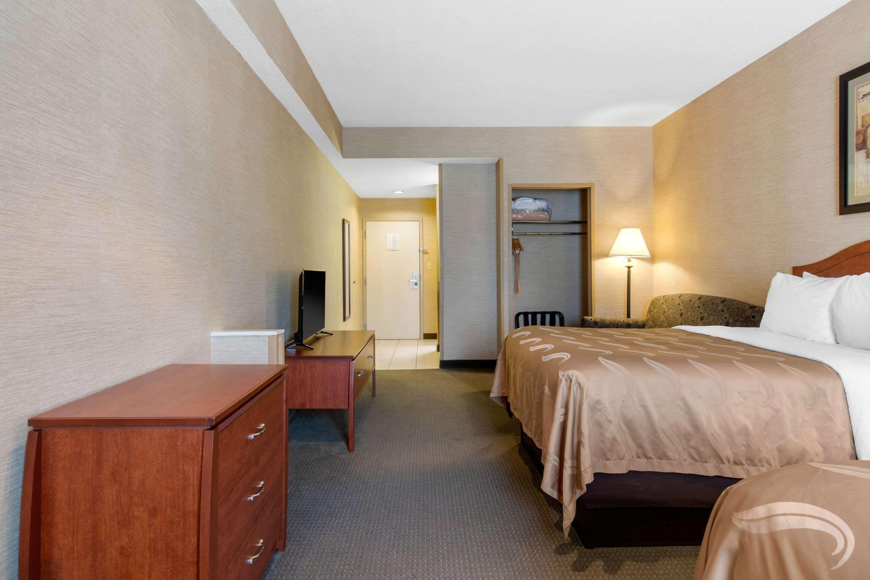 Ein Hotelzimmer mit einem Bett, einem Schreibtisch, einem Fernseher und einem Kleiderschrank.