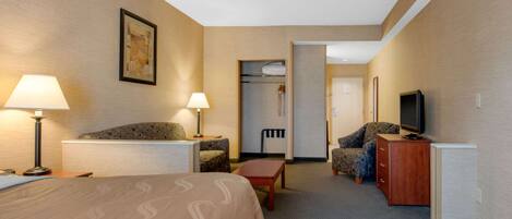 A hotel room with a bed, two bedside lamps, a television, a desk, a chair, and a wardrobe.