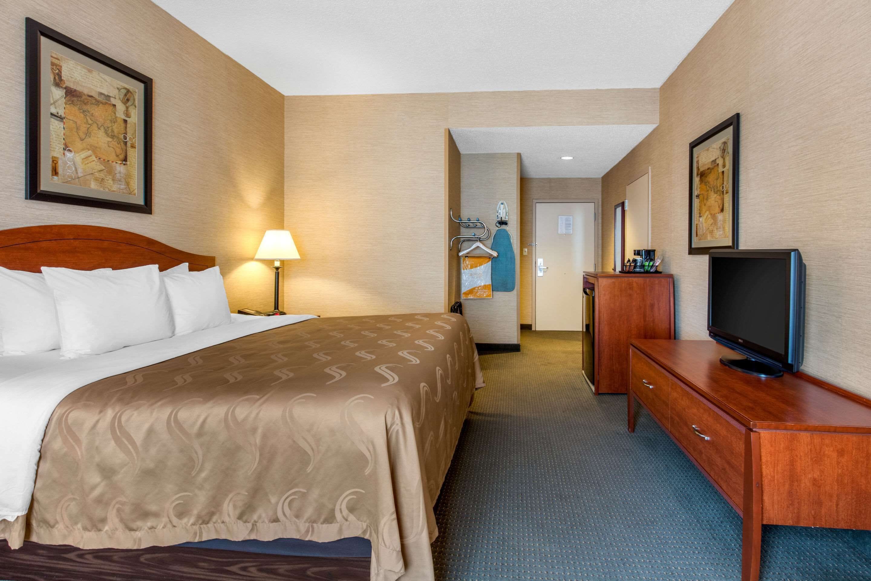 Une chambre d’hôtel avec un grand lit, une télévision, un bureau et un miroir.