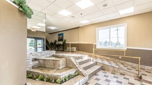 A hotel lobby with a stone staircase, a large window, and a view of the outdoors. - Park Inn by Radisson, Detroit Metro Airport (Romulus)