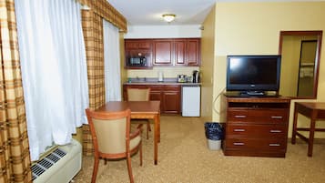 Une chambre d’hôtel compacte comprenant un coin cuisine, un espace repas, une télévision et un petit bureau.