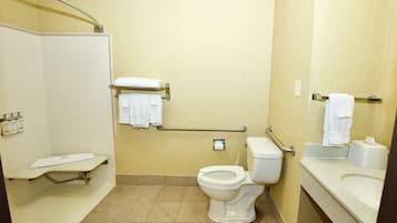 A bathroom with a shower, toilet, and sink, equipped with grab bars and a towel rack.