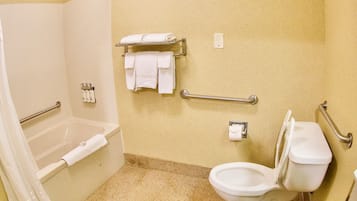 Et badeværelse med bruser, toilet, gelænder og et håndklædetørrestativ.