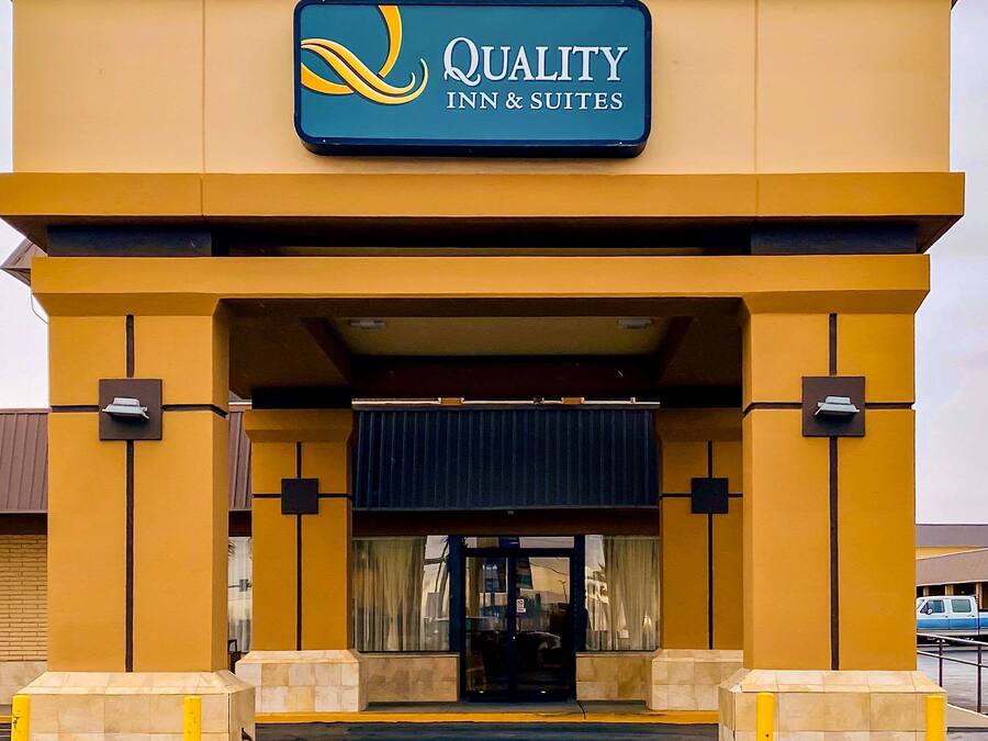 The exterior of a Quality Inn & Suites with a prominent sign, entrance, and a parking area.