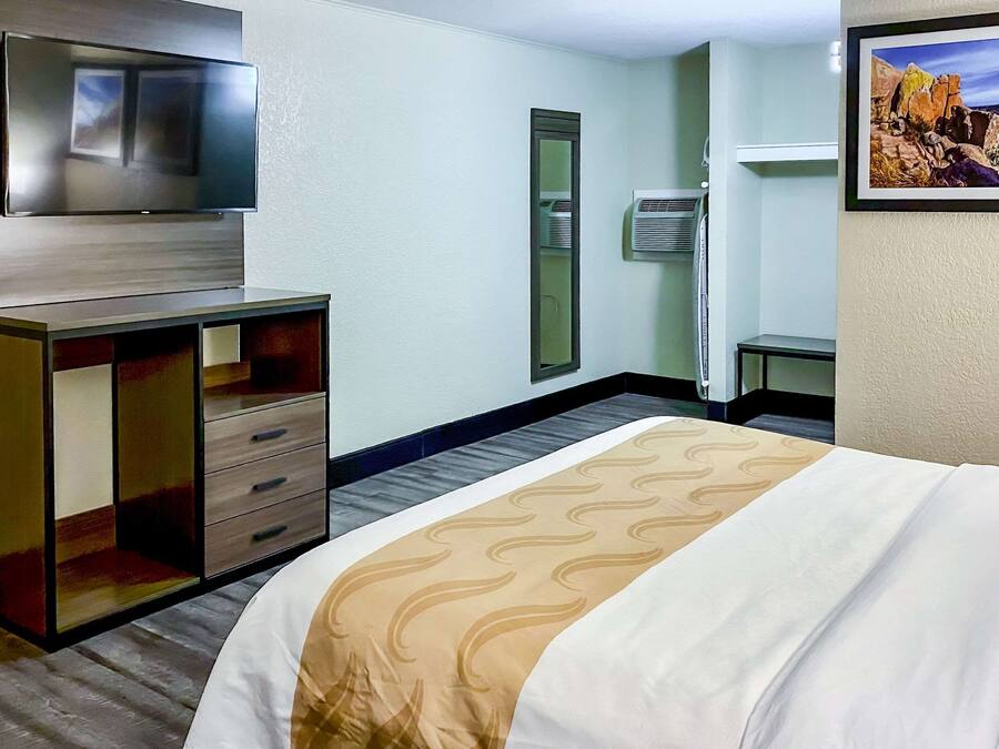 Ein Hotelzimmer mit Bett, Fernseher, Spiegel und einem Bild an der Wand.