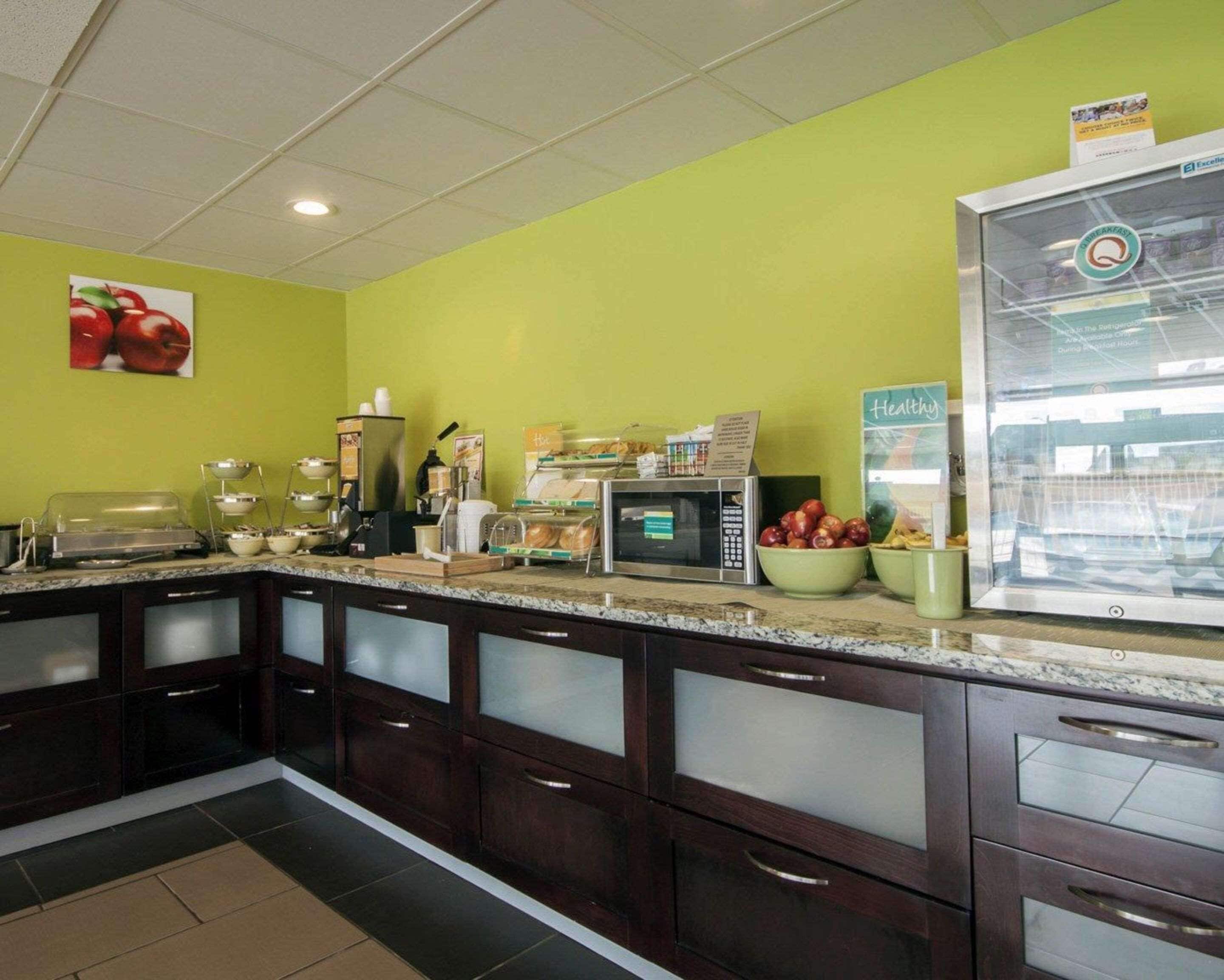 A breakfast area with a microwave, coffee station, and a fruit bowl.