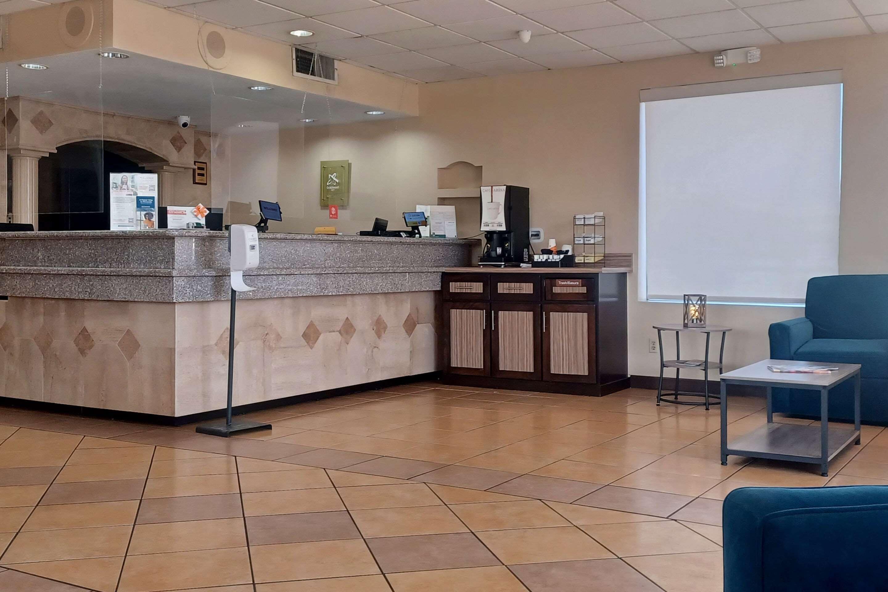 A reception area with a counter, a coffee machine, a projector screen, and a blue sofa.