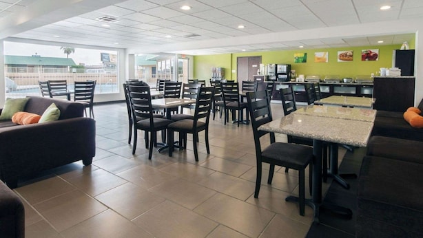 Un restaurant spacieux avec de hauts plafonds, des sols carrelés et différents types de sièges, notamment des tables et des chaises.