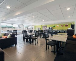 Um restaurante espaçoso com pé-direito alto, piso em azulejos e diversos tipos de assentos, incluindo mesas e cadeiras.