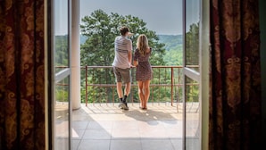 A couple standing on a balcony with a view of a forested landscape. - The Crescent Hotel and Spa (Eureka Springs)