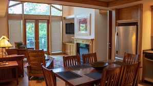 A dining area with wooden furniture, a fireplace, and a kitchen with a refrigerator. - The Crescent Hotel and Spa (Eureka Springs)