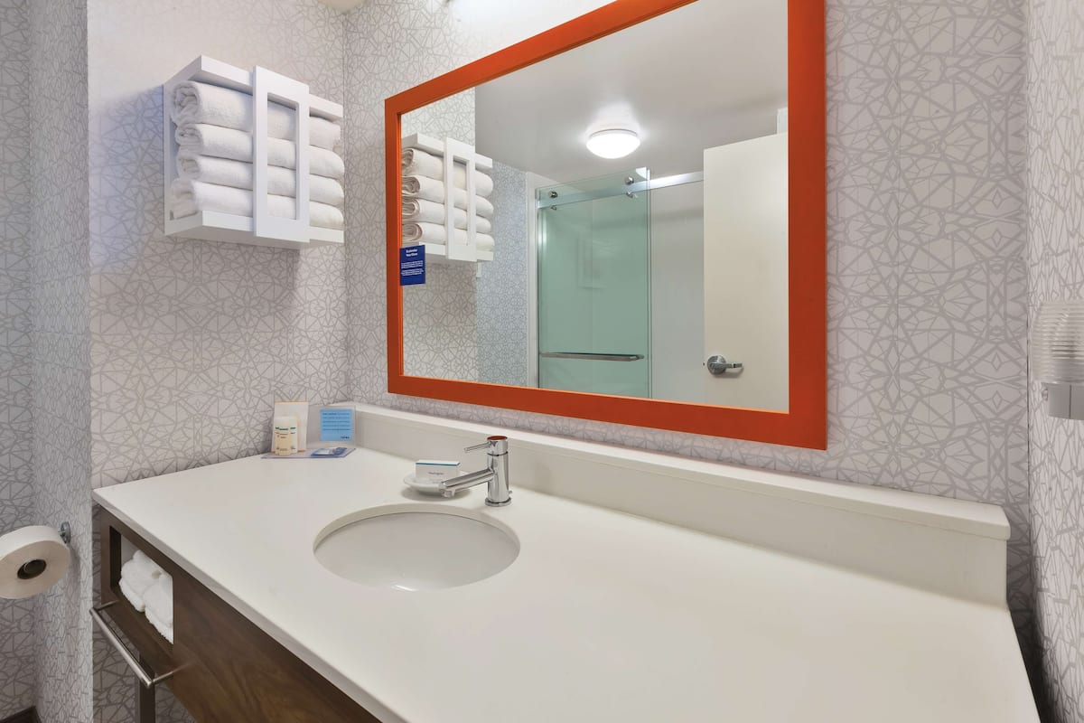 A bathroom with a white sink, a mirror with a red frame, and a towel rack.