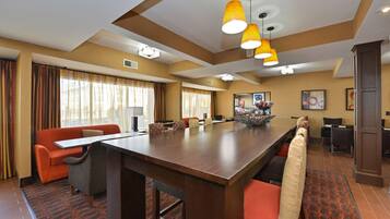 A conference room with a long table, orange chairs, and a large window with curtains.