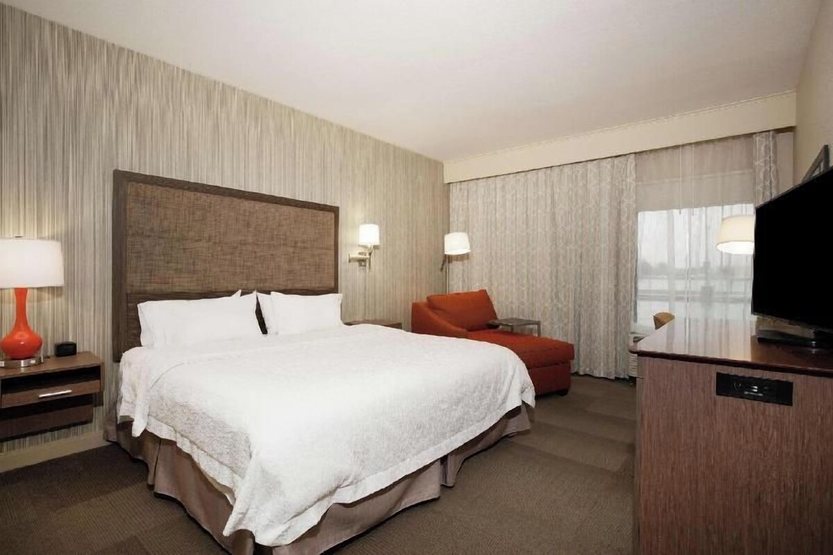 Una habitación de hotel con una cama grande, un escritorio, un televisor y una silla.