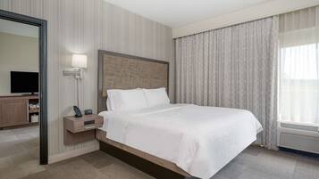 Una habitación de hotel con una cama grande, una mesita de noche con lámpara, un televisor y un armario.
