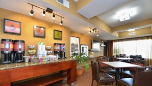A hotel dining area with a buffet setup, including coffee makers and a potted plant. - Hampton Inn Collinsville (Collinsville)