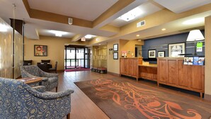 A lobby with patterned chairs, a reception desk, and a carpet with a floral design. - Hampton Inn Collinsville (Collinsville)