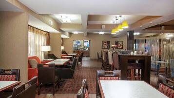 Comedor de hotel con cabinas y mesas, zona de bar y vistas a la ciudad.