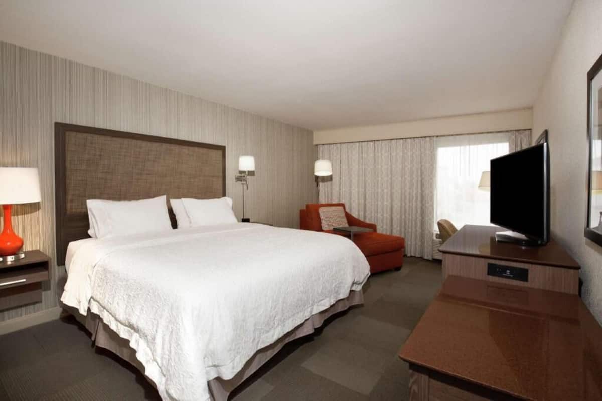 A hotel room with a large bed, a television, a desk, and a chair.