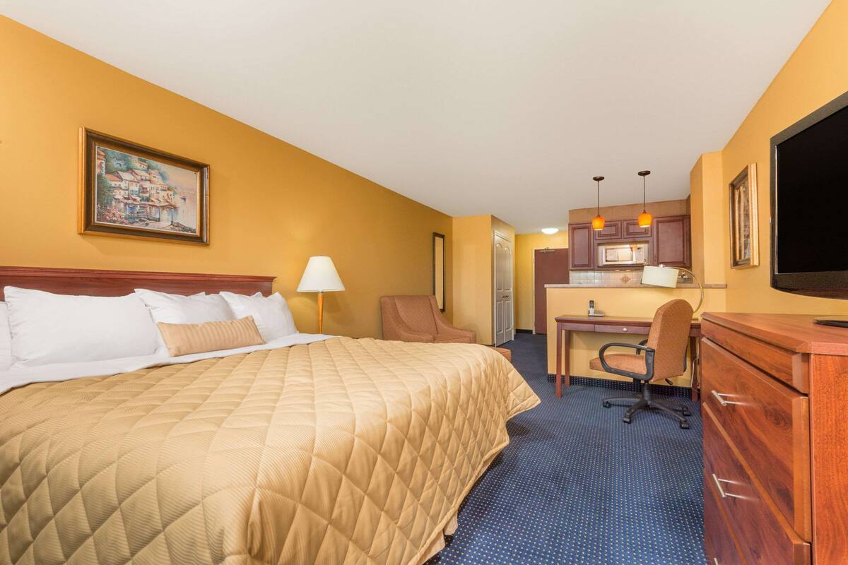 Een hotelkamer met een bed, bureau, stoel en kitchenette.