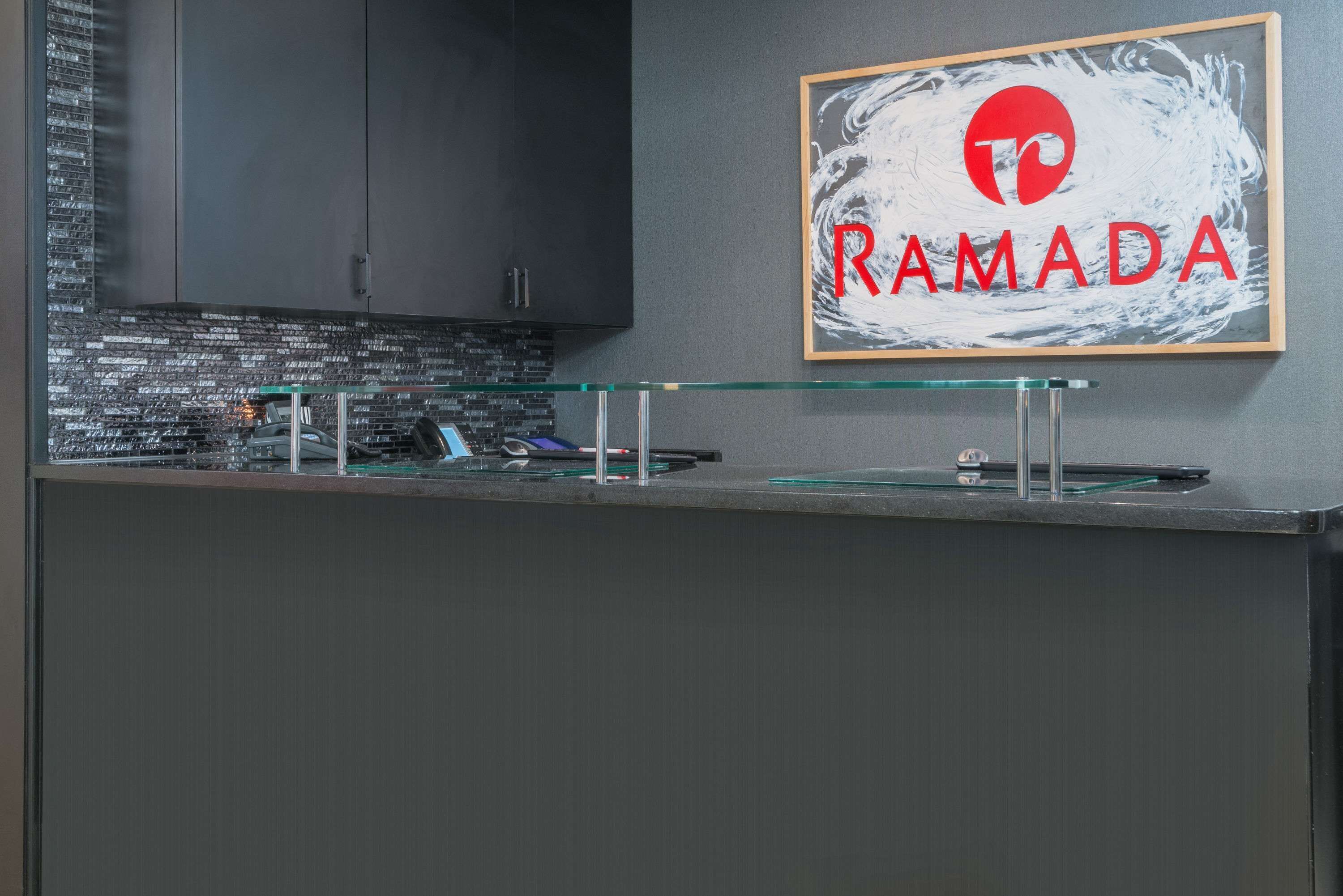 Una cocina moderna con gabinetes oscuros, un protector de vidrio en la pared y un letrero enmarcado que dice "RAMADA".