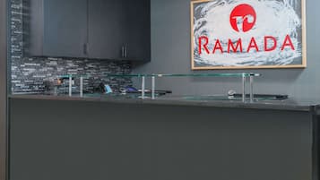 Una cocina moderna con gabinetes oscuros, un protector de vidrio en la pared y un letrero enmarcado que dice "RAMADA".