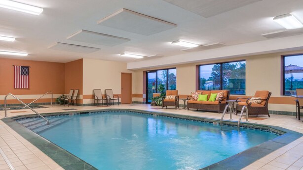 An indoor swimming pool with lounge chairs and a view of the outside.
