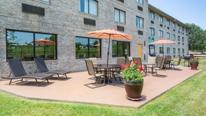A hotel patio with outdoor seating, large windows, and a brick facade.