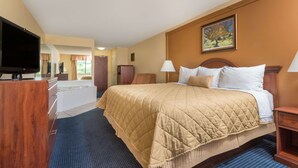 A hotel room with a large bed, a television, a desk, and a bathroom visible through an open door.