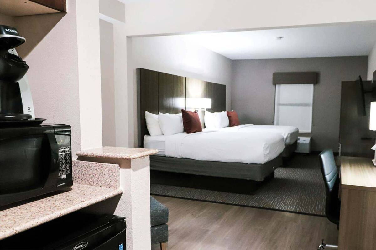 A hotel room with a bed, a desk, a chair, a television, and a microwave.