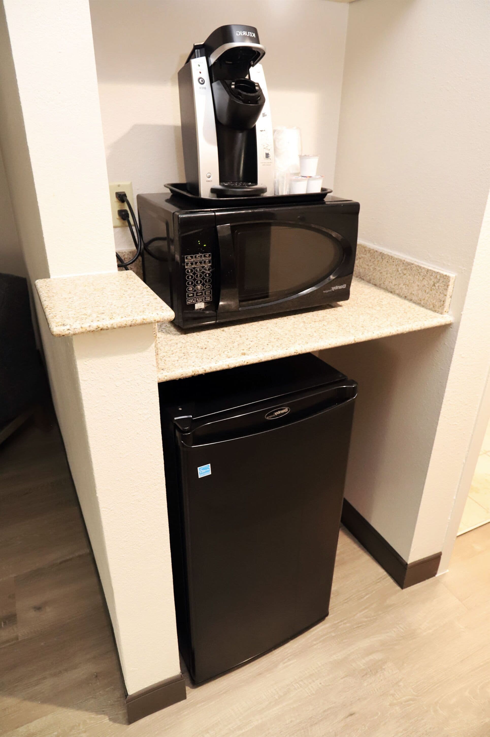 A compact kitchenette with a microwave, coffee maker, and a small refrigerator.