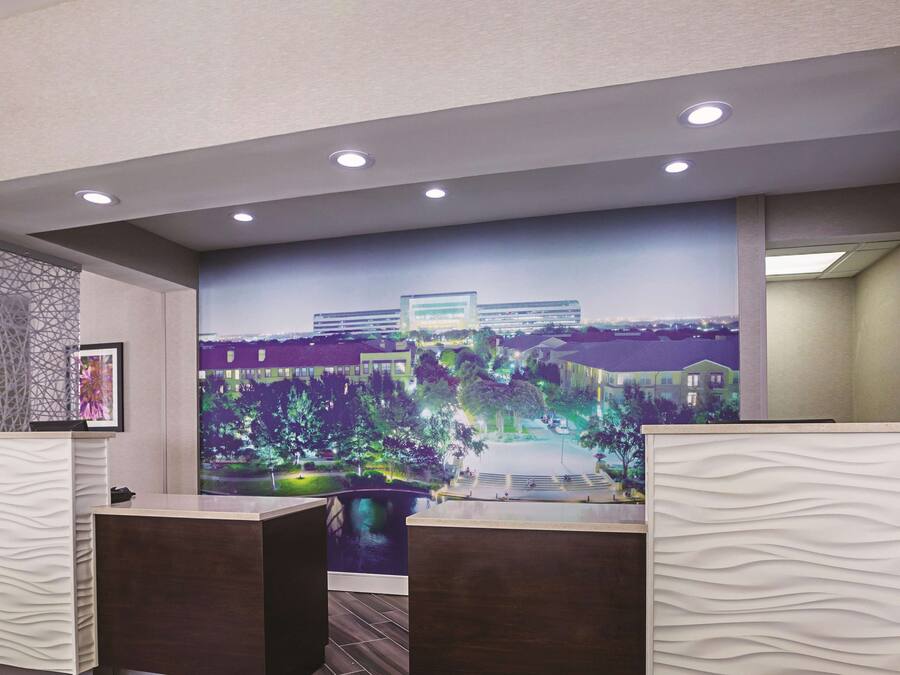 A reception area with a large mural of a cityscape, a modern reception desk, and a view of the outdoors.